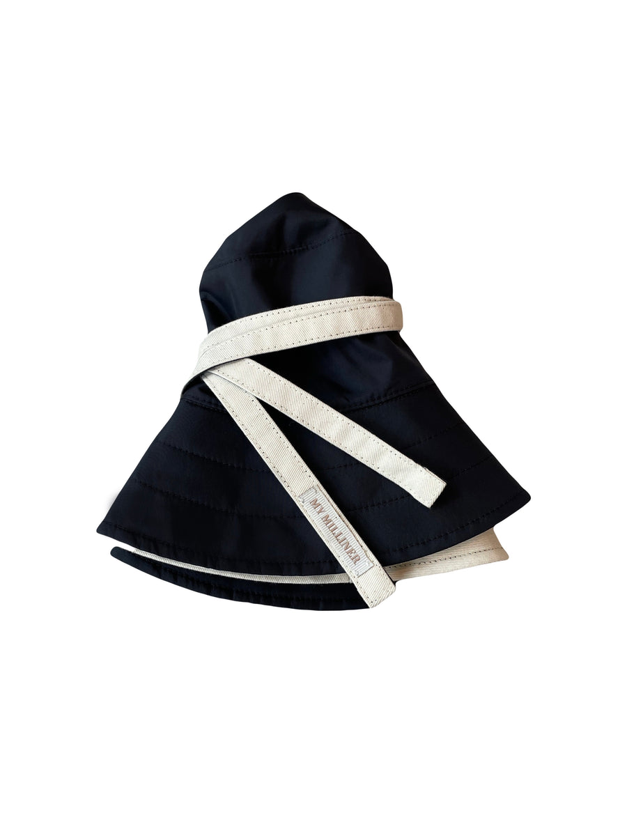 Reversible black and cream bucket hat with ties for high-wind conditions.